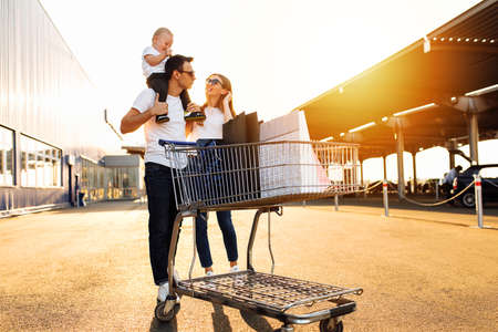 Happy family with child with shopping bags and shopping trolley on the street against the background of a shopping mall, shoppingの写真素材