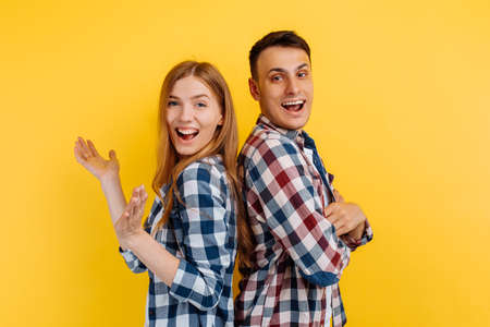 young couple, man and woman clap their hands and applaud on yellow backgroundの写真素材