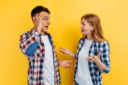 couple man and woman quarreling and shouting at each other on yellow background, quarrel conceptの写真素材