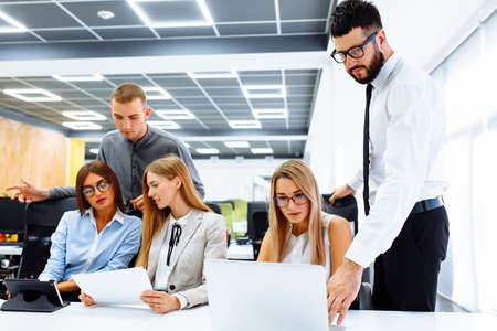 Business team working on a new project and smiling while sitting at their desk in modern office