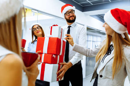business people wearing Santa Claus hats while celebrating Christmas in the officeの写真素材