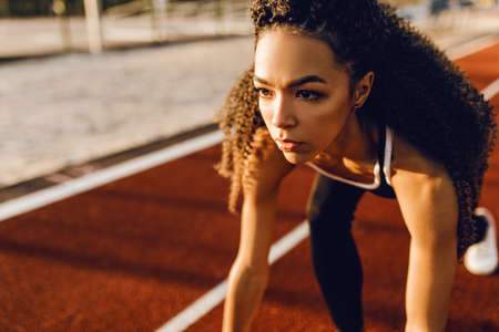 Young sportive woman runner at stadium starting line getting ready for race, sport conceptの写真素材