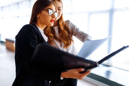 Young happy business colleagues communicate while walking along the corridor in the office with a folder with documentsの写真素材