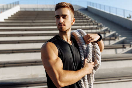 Sporty man doing fitness workout outdoors, muscular man using two fighting ropes, sport, motivationの写真素材