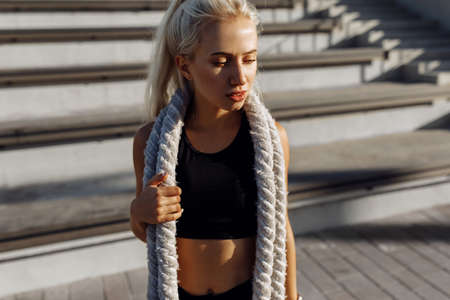 Sportive young confident woman, in sportswear, with fighting ropes, outdoors against the background...