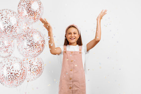 Happy excited little girl celebrating and exploding up colorful confetti, over isolated white backgroundの写真素材