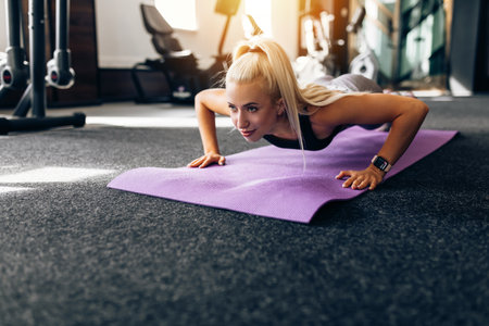 slender young woman doing push-ups in the gym, on the fitness mat. Sport, healthy lifestyleの写真素材