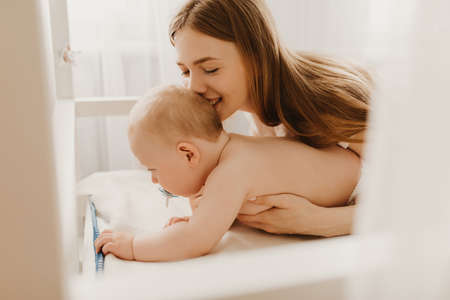 Happy smiling mother and baby lying on bed at home, top viewの写真素材