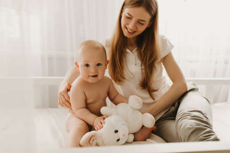happy loving family. mom plays with her baby in the bedroomの写真素材