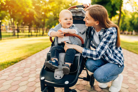 Young beautiful mother, with her little cute child, walking in the park on a sunny summer day.