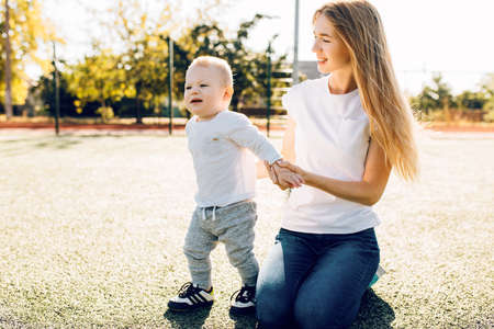 Happy family, mom and her little child together outdoors in the park on the lawn, Mother's Day