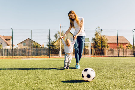 Happy family, mom and child playing soccer on the soccer fieldの写真素材