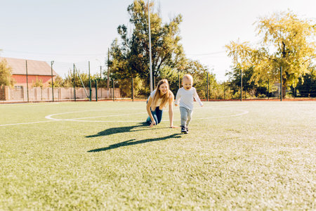 Happy mother and her little son playing outdoors on the grass, mom and her cheerful child are having fun in the park, Portrait of a happy familyの写真素材
