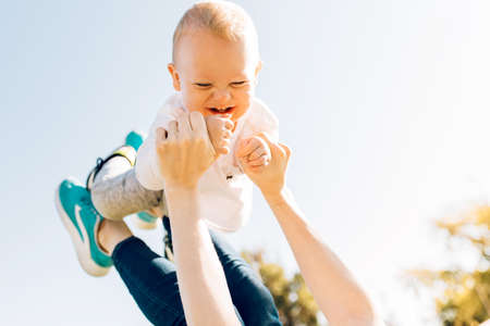 mom playing and throwing up happy little son while having fun together in the park