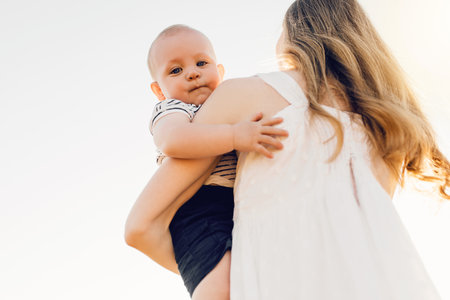 Happy family outdoors, mother throws the baby up, laughs and plays in the summer on natureの写真素材