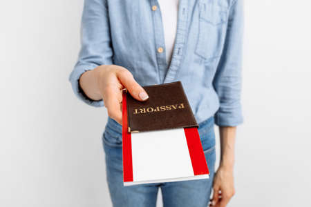 Portrait of happy young woman holding travel tickets and passport isolated on white backgroundの写真素材