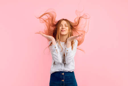 Excited happy young woman, raising palms of joy, shouting loudly, wearing casual white t-shirt, over isolated pink backgroundの写真素材