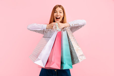 Happy beautiful young woman, with shopping bags enjoy shopping, isolated on pink background