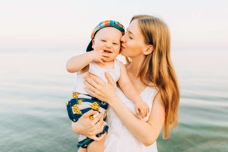 Young beautiful mother playing on the beach with her little cute sonの写真素材
