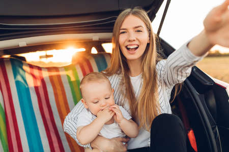 Vacation, Travel - family ready to go on summer vacation, Happy mom with a small child in the trunk...