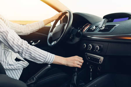 Beautiful young happy smiling woman driving her new car at sunset