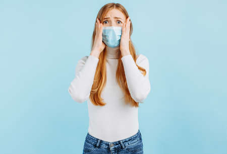 Excited young woman looking wide eyes at camera covering mouth with hands on isolated blue studio...