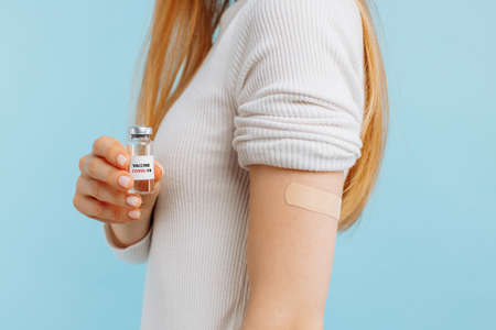 Healthy young woman in medical mask vaccinated, immunity, blue background, recommended vaccination concept, vaccination, vaccinated patient, vaccine deployment programの写真素材