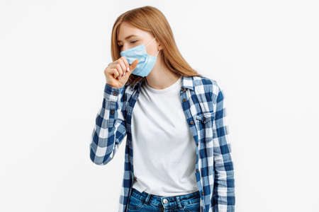 Young woman in medical protective mask suffering from cough and feeling unwell over i white backgroundの写真素材