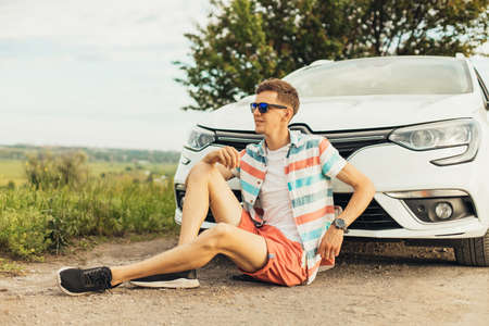 Travel - young handsome happy man in sunglasses, travels by car, rent a car on vacation, travel...