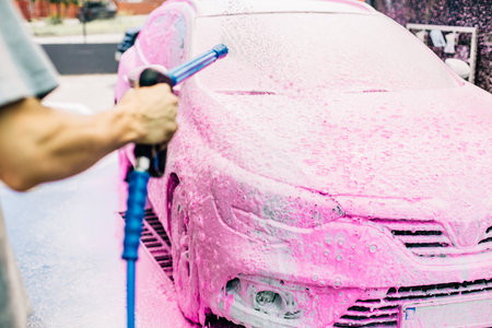 Manual car wash with pressure water on the street, Summer car wash, Car wash with high pressure water, Car wash with pink foamの写真素材
