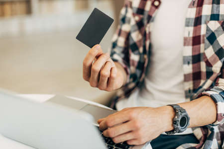 Close-up of man holding credit card and using laptop, concept of online shopping, online payment
