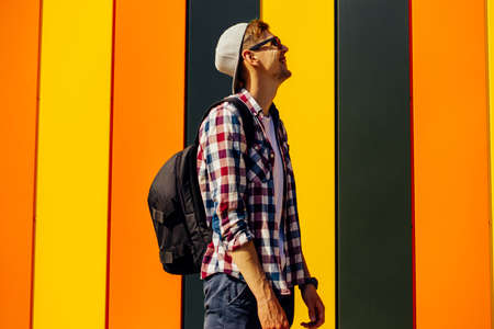Side view of an excited young hipster guy in trendy clothes, with half-sleeve, posing isolated on a...
