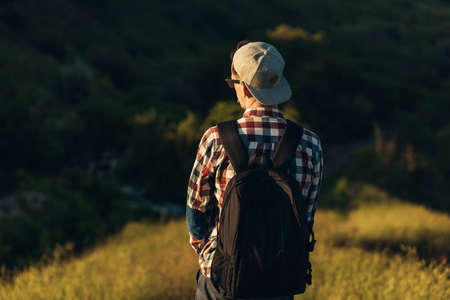 Young traveling man, handsome man in glasses and in a cap, with a backpack, walking in the forests of nature, hiking, active people, in natureの写真素材