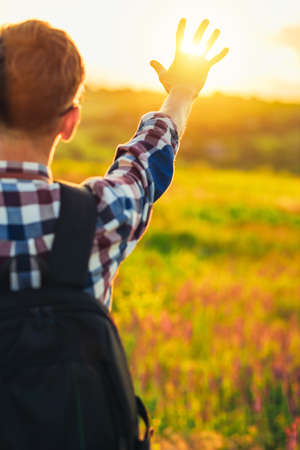 Back view, Human hand, tourist covering sunlight, Sun shining through hand, Human hand and sun, travel concept, tourismの写真素材