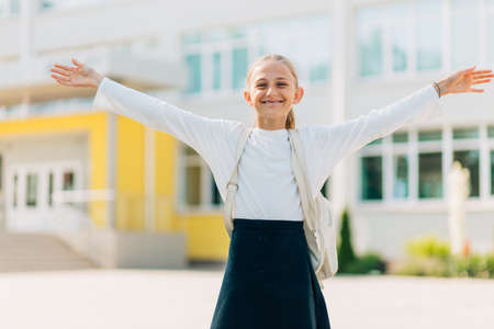 Primary school student, Happy girl with a backpack near the building outdoors, Start of lessons, The first day of autumn.の写真素材