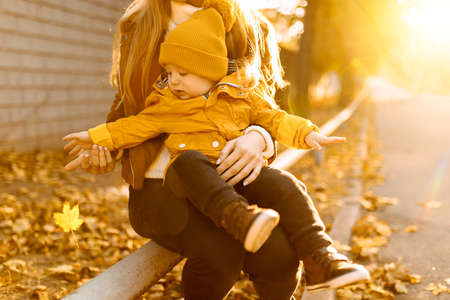 Happy mother and little son are playing and having fun outdoors on the background of an autumn park, family, childhood conceptの写真素材