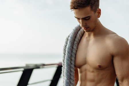 Strong man training with fighting ropes, Sportsman doing battle rope training outdoors on the sea on the pier, sports, motivationの写真素材