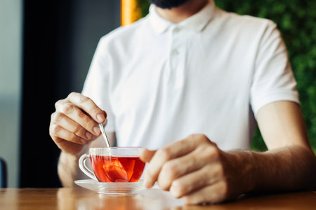 man drinking aromatic tea during lunch break in cafe, young man enjoying delicious hot drink holding cupの写真素材