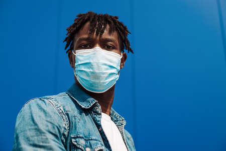 portrait of an afro american black man wearing a protective mask from the coronavirus, blue...