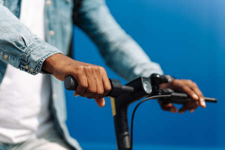 closeup steering wheel of an electric scooter man rides outdoors, against background of a blue buildingの写真素材