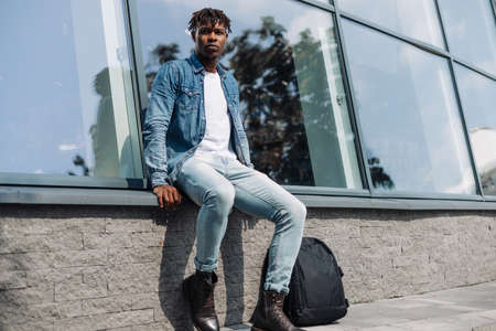 portrait of a black man African American in the city against the background of a glass building of a university or business center, with a backpackの写真素材