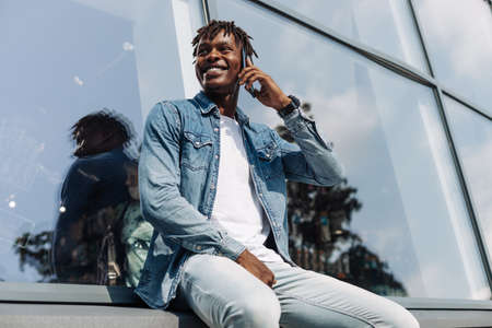 African American man talking on the phone, against the background of a glass building, African businessman with a mobile phoneの写真素材