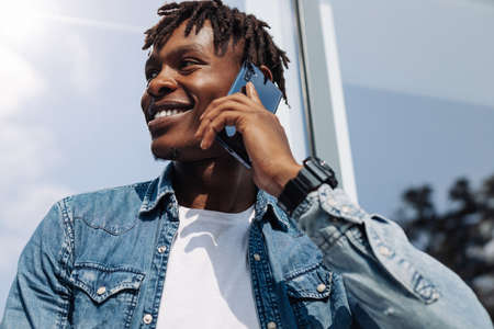 African American man talking on the phone, against the background of a glass building, African student with a mobile phoneの写真素材