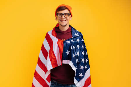 handsome man with an orange hat on his head with glasses and a red witer, holding moisture in his...