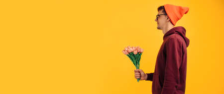 closeup of a bouquet of flowers, a man gives a bouquet of pink tulips, on a yellow backgroundの写真素材