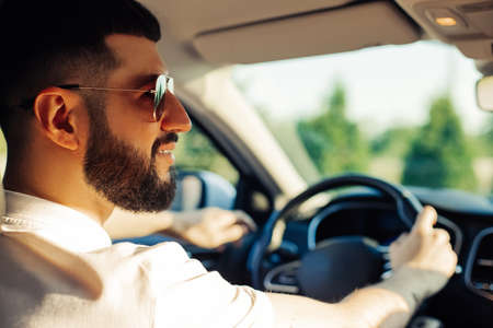 Male driver buying a new car makes a test drive while choosing a new car in a car dealership storeの写真素材