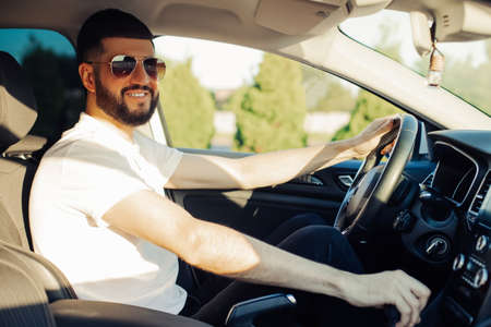 Male driver buying a new car makes a test drive while choosing a new car in a car dealership storeの写真素材