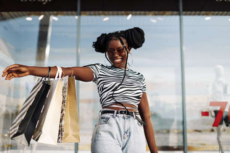 Happy beautiful young African American woman wearing black glasses, with black shopping bags, Black Friday, sale, fashion, peopleの写真素材