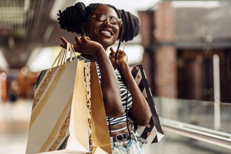 Young African American beautiful woman, with shopping bags walking in the mall, consumerism, selling, shoppingの写真素材