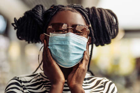 African American woman wearing a medical protective mask, Young woman wearing a protective face mask to protect against coronavirus, a woman wearing a mask during the COVID-19 coronavirus pandemicの写真素材
